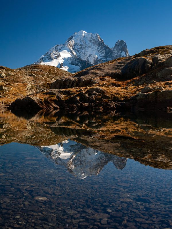 Aiguille Verte from Mont Blanc massif reflecting on the water in Chamonix, France A vertical shot of the Aiguille Verte from Mont Blanc massif reflecting on the water in Chamonix, France